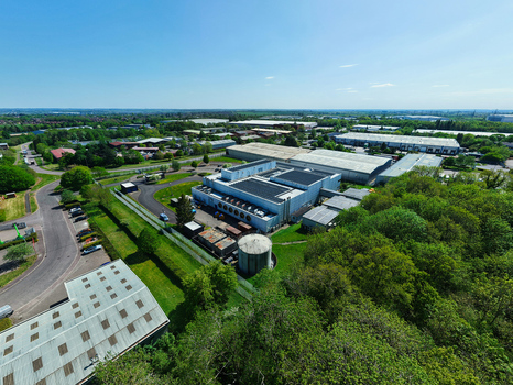 Aerial view of a data centre facility with cooling systems industrial warehouses and surrounding green trees under a clear blue sky Wellingborough England United Kingdom. Aerial view of a data centre facility with cooling systems industrial warehouses and surrounding green trees under a clear blue sky Wellingborough England United Kingdom.