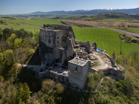 Aerial view of the medieval ruins of Castle Likava on a rocky hill surrounded by green fields and forests with a highway bridge in the background Likavka Zilina Region Slovakia. Aerial view of the medieval ruins of Castle Likava on a rocky hill surrounded by green fields and forests with a highway bridge in the background Likavka Zilina Region Slovakia.