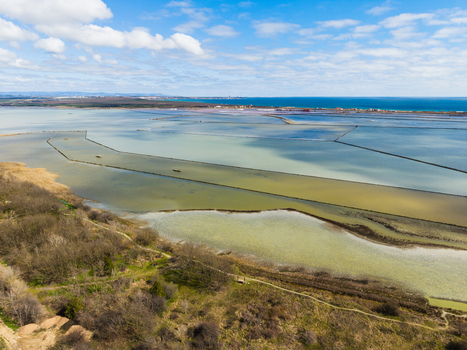 Aerial view of the colorful salt pans of Lake Atanasovsko with the Black Sea coast under a blue sky in Burgas Burgas Bulgaria. Aerial view of the colorful salt pans of Lake Atanasovsko with the Black Sea coast under a blue sky in Burgas Burgas Bulgaria.