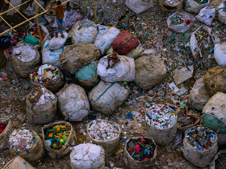 Keraniganj Bangladesh 20 May 2026 Aerial view of workers and children sitting on large white sacks filled with plastic waste at a recycling site near the Buriganga River. Keraniganj Bangladesh 20 May 2026 Aerial view of workers and children sitting on large white sacks filled with plastic waste at a recycling site near the Buriganga River.