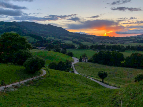 14 May 2026 Aerial view of rolling green hills and a winding road through a rural landscape at sunset with an orange glow in the sky. 14 May 2026 Aerial view of rolling green hills and a winding road through a rural landscape at sunset with an orange glow in the sky.