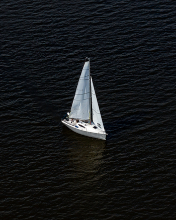 Aerial view of a white sailboat gliding across the dark waters of the Vistula river during a yacht race in Plock Masovian Voivodeship Poland.