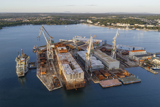 Aerial view of Uljanik Shipyard with large industrial cranes ship construction structures and metal components along the waterfront during golden hour in Pula Istarska zupanija Croatia. Aerial view of Uljanik Shipyard with large industrial cranes ship construction structures and metal components along the waterfront during golden hour in Pula Istarska zupanija Croatia.