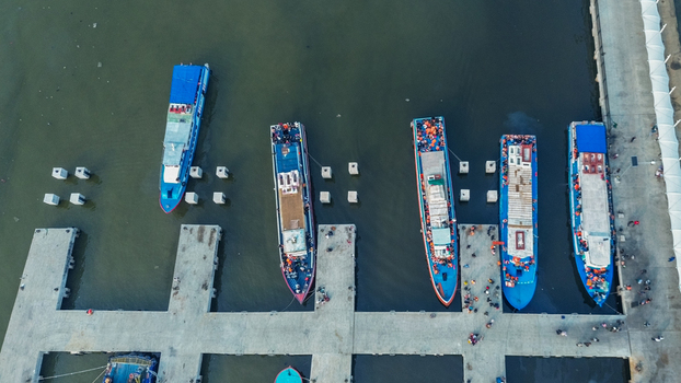 Aerial view of Port of Kali Adem with wooden fishing boats docked at the pier and surrounding industrial infrastructure in Kecamatan Penjaringan Daerah Khusus Ibukota Indonesia. Aerial view of Port of Kali Adem with wooden fishing boats docked at the pier and surrounding industrial infrastructure in Kecamatan Penjaringan Daerah Khusus Ibukota Indonesia.