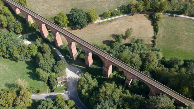 Aerial view of the historic Himbachel Viadukt railway bridge surrounded by lush forests and green fields in Erbach Hessen Germany.