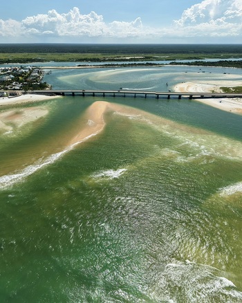 Aerial view of Matanzas Inlet featuring the bridge spanning the turquoise waters with sandy shoals and coastal vegetation in St. Johns County Florida United States. Aerial view of Matanzas Inlet featuring the bridge spanning the turquoise waters with sandy shoals and coastal vegetation in St. Johns County Florida United States.