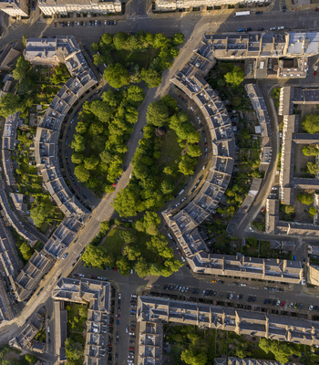 Aerial view of circle of Georgian housing in Edinburgh with circle of trees and road at sunset