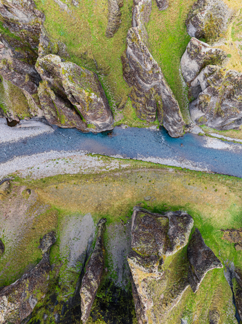Aerial view of the deep Fjadrargljufur canyon with a river flowing through steep moss covered rock formations in Iceland. Aerial view of the deep Fjadrargljufur canyon with a river flowing through steep moss covered rock formations in Iceland.