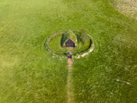 Aerial view of a traditional Icelandic turf church with a grass covered roof situated within a circular earthen enclosure in a vast green meadow in Iceland. Aerial view of a traditional Icelandic turf church with a grass covered roof situated within a circular earthen enclosure in a vast green meadow in Iceland.