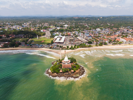 Aerial view of Parevi Duwa Temple on a rocky island surrounded by turquoise ocean waves and the coastal skyline Matara Southern Province Sri Lanka. Aerial view of Parevi Duwa Temple on a rocky island surrounded by turquoise ocean waves and the coastal skyline Matara Southern Province Sri Lanka.