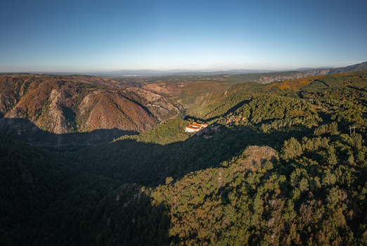 Aerial view of the historic Monastery of Santo Estevo de Ribas de Sil nestled within the lush forested hills of the Ribeira Sacra region in O Covelo Ourense Spain.