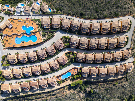 Aerial view of a residential complex with terraced houses terracotta roofs and swimming pools in Moraira Valencian Community Spain.