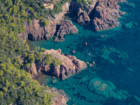 Aerial view of the red rock cliffs and turquoise waters of Le Trayas with people kayaking along the coastline Saint Raphael Provence Alpes Cote d Azur France. Aerial view of the red rock cliffs and turquoise waters of Le Trayas with people kayaking along the coastline Saint Raphael Provence Alpes Cote d Azur France.