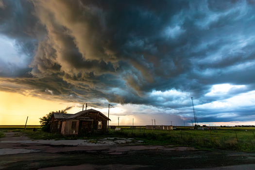 View of a dramatic storm front with dark swirling clouds over a rural landscape and an old house in Oklahoma City Oklahoma United States.