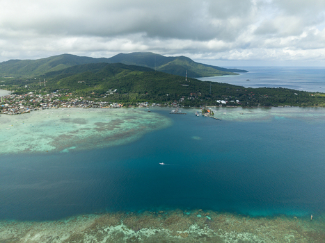 Aerial view of the vibrant turquoise waters meeting the lush green island a tropical paradise revealed from above Karimunjawa Central Java Indonesia. Aerial view of the vibrant turquoise waters meeting the lush green island a tropical paradise revealed from above Karimunjawa Central Java Indonesia.
