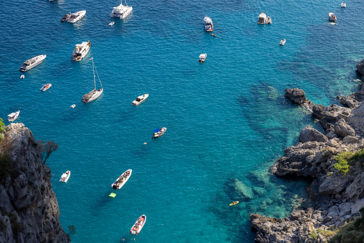Aerial view of boats anchored in the turquoise waters of the Mediterranean Sea near the rocky cliffs of Capri Campania Italy. Aerial view of boats anchored in the turquoise waters of the Mediterranean Sea near the rocky cliffs of Capri Campania Italy.