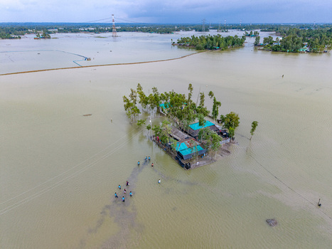 Aerial view of flooded houses surrounded by water with trees and people wading through the floodwaters in Banshkhali Upazila Chittagong Division Bangladesh. Aerial view of flooded houses surrounded by water with trees and people wading through the floodwaters in Banshkhali Upazila Chittagong Division Bangladesh.