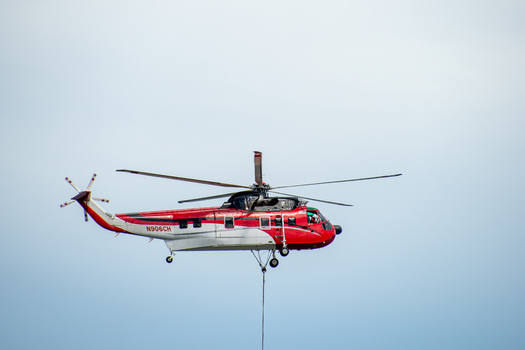 Miami Florida United States 22 September 2026 Aerial view of a red and white helicopter flying against a clear sky carrying a long line for external load operations.