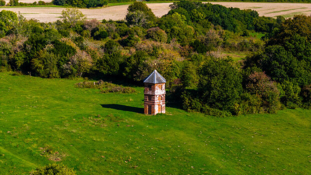 Aerial view of the historic Pepperbox Folly standing in a lush green field surrounded by trees and rolling hills in Salisbury England United Kingdom. Aerial view of the historic Pepperbox Folly standing in a lush green field surrounded by trees and rolling hills in Salisbury England United Kingdom.