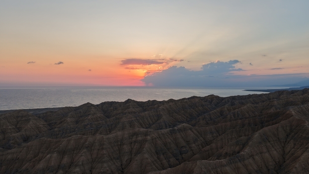 Aerial view of Issyk Kul lake at sunset with rugged mountain terrain in the foreground and a dramatic colorful sky in Issyk Kul Region Kyrgyzstan. Aerial view of Issyk Kul lake at sunset with rugged mountain terrain in the foreground and a dramatic colorful sky in Issyk Kul Region Kyrgyzstan.