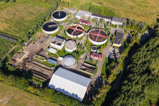 Aerial view of a wastewater treatment plant with circular sedimentation tanks industrial buildings and surrounding green fields in Pomeranian Voivodeship Poland. Aerial view of a wastewater treatment plant with circular sedimentation tanks industrial buildings and surrounding green fields in Pomeranian Voivodeship Poland.