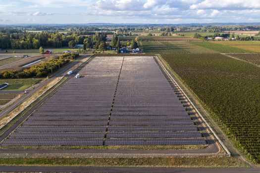 Aerial view of a large solar farm installation in rural farmland featuring rows of photovoltaic panels surrounded by agricultural fields and trees in Woodburn Oregon United States. Aerial view of a large solar farm installation in rural farmland featuring rows of photovoltaic panels surrounded by agricultural fields and trees in Woodburn Oregon United States.