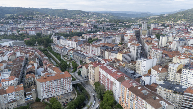 Aerial view of the urban landscape with dense residential buildings red tiled roofs and a river winding through the city center under a cloudy sky in Ourense Province of Ourense Spain.