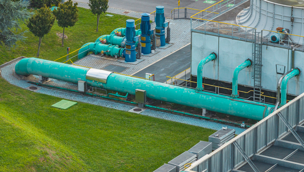 Aerial view of industrial water cooling and pumping system with large turquoise pipelines electric pumps and cooling infrastructure at a manufacturing plant in Brescia Lombardy Italy.