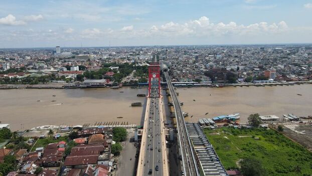 Aerial view of the iconic red Ampera Bridge spanning the Musi River with urban cityscape traffic and railway tracks in Kecamatan Seberang Ulu I Sumatera Selatan Indonesia. Aerial view of the iconic red Ampera Bridge spanning the Musi River with urban cityscape traffic and railway tracks in Kecamatan Seberang Ulu I Sumatera Selatan Indonesia.