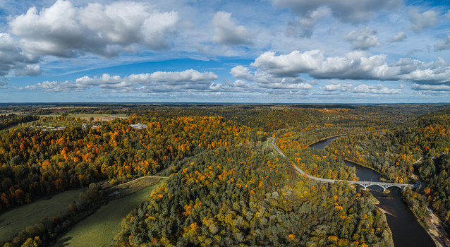 Aerial view of the Sigulda landscape featuring the winding Gauja River a stone bridge and vibrant autumn foliage in the dense forests of Sigulda Sigulda Municipality Latvia. Aerial view of the Sigulda landscape featuring the winding Gauja River a stone bridge and vibrant autumn foliage in the dense forests of Sigulda Sigulda Municipality Latvia.