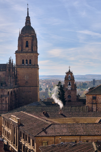 Salamanca Spain 01 December 2025 View of the Pontifical University of Salamanca towers and historic rooftops with smoke rising from a chimney under a clear blue sky. Salamanca Spain 01 December 2025 View of the Pontifical University of Salamanca towers and historic rooftops with smoke rising from a chimney under a clear blue sky.