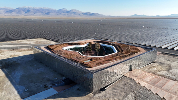 Aerial view of the Karapinar Solar Power Plant featuring a central modern building with a green roof surrounded by vast solar panels in the arid landscape of Karapinar Konya Turkiye.