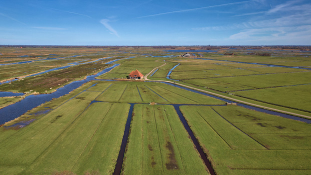 Aerial view of the vibrant green and brown patchwork of farmland and waterways creates a stunning contrast under the clear blue sky Wormer Netherlands. Aerial view of the vibrant green and brown patchwork of farmland and waterways creates a stunning contrast under the clear blue sky Wormer Netherlands.