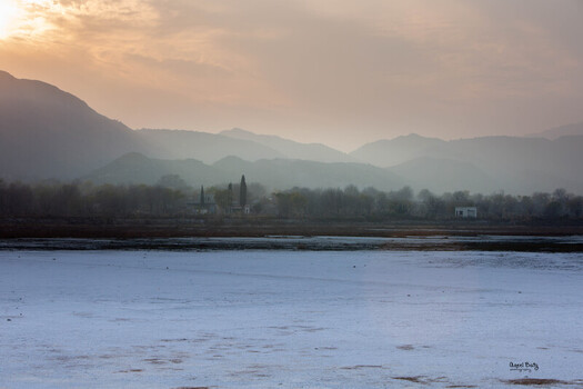 View of a serene landscape with a shimmering lake reflecting the soft light of the dawn with mountains in the backdrop Uchhali Lake. View of a serene landscape with a shimmering lake reflecting the soft light of the dawn with mountains in the backdrop Uchhali Lake.