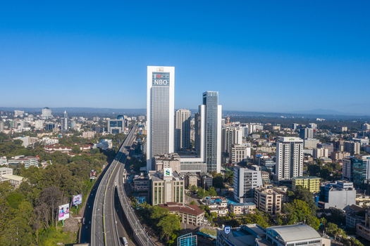 Aerial view of Westlands district featuring modern skyscrapers including the NBO tower and a major highway winding through the urban landscape of Nairobi Nairobi County Kenya. Aerial view of Westlands district featuring modern skyscrapers including the NBO tower and a major highway winding through the urban landscape of Nairobi Nairobi County Kenya.