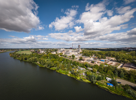 Opole Poland 06 September 2026 Aerial view of Cement Odra SA industrial plant along the Oder river featuring factory buildings chimneys and green trees under a blue sky. Opole Poland 06 September 2026 Aerial view of Cement Odra SA industrial plant along the Oder river featuring factory buildings chimneys and green trees under a blue sky.