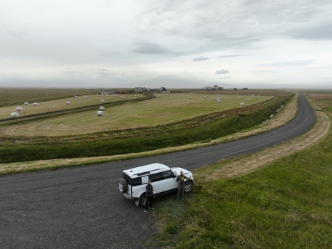 Aerial view of a white SUV parked on a gravel road next to a field with hay bales in the Icelandic countryside near Selfoss Sveitarfelagid Arborg Iceland. Aerial view of a white SUV parked on a gravel road next to a field with hay bales in the Icelandic countryside near Selfoss Sveitarfelagid Arborg Iceland.