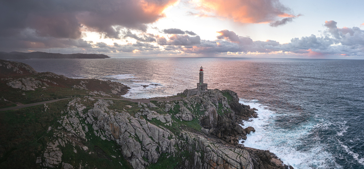 Aerial view of Faro de Punta Nariga lighthouse on a rugged rocky cliff with waves crashing against the shore under a dramatic sunset sky Malpica A Coruna Spain. Aerial view of Faro de Punta Nariga lighthouse on a rugged rocky cliff with waves crashing against the shore under a dramatic sunset sky Malpica A Coruna Spain.