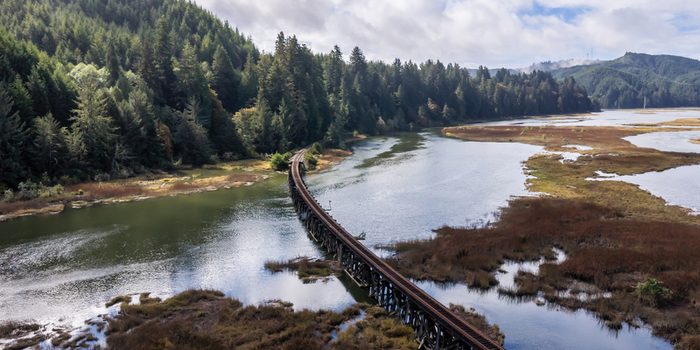 Aerial view of the Coos Bay Rail Line running through wetlands near Florence Oregon highlighting a coastal rail corridor in a low lying marsh landscape along the Siuslaw River.