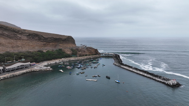 Aerial view of the fishing harbor in Chorrillos with boats anchored in the bay protected by a stone breakwater against the Pacific Ocean Chorrillos Provincia de Lima Peru.