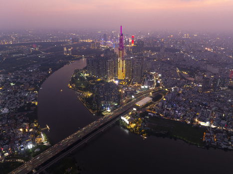 Aerial view of Landmark 81 skyscraper and the Saigon River illuminated by city lights under a twilight sky in Ho Chi Minh City Ho Chi Minh Vietnam. Aerial view of Landmark 81 skyscraper and the Saigon River illuminated by city lights under a twilight sky in Ho Chi Minh City Ho Chi Minh Vietnam.