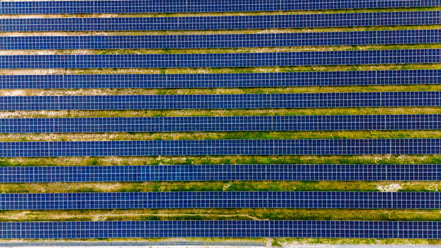 Aerial view of rows of blue solar panels in a large photovoltaic power plant with green grass between the structures in Sabac Vojvodina Serbia.