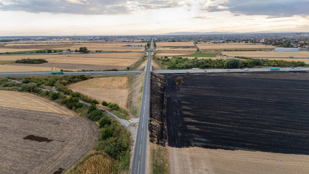 Aerial view of a rural road intersection surrounded by agricultural fields including a section of scorched earth under a cloudy sky in Sremska Mitrovica Vojvodina Serbia.