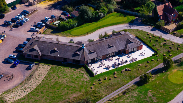 Aerial view of Hamptworth Golf clubhouse featuring a spacious patio with outdoor seating surrounded by lush green fairways and a parking area in Hamptworth England United Kingdom. Aerial view of Hamptworth Golf clubhouse featuring a spacious patio with outdoor seating surrounded by lush green fairways and a parking area in Hamptworth England United Kingdom.