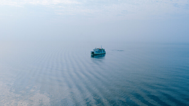 Aerial view of a passenger ferry boat sailing across the calm misty waters of the sea in Dumaguete City Negros Island Region Philippines. Aerial view of a passenger ferry boat sailing across the calm misty waters of the sea in Dumaguete City Negros Island Region Philippines.