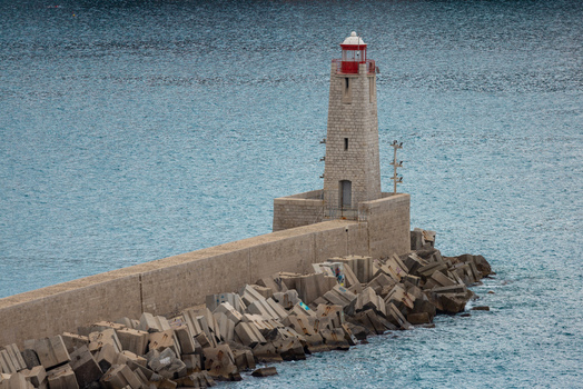 Aerial view of the historic lighthouse at the port of Nice featuring a stone tower with a red lantern situated at the end of a breakwater in Nice Provence Alpes Cote d Azur France. Aerial view of the historic lighthouse at the port of Nice featuring a stone tower with a red lantern situated at the end of a breakwater in Nice Provence Alpes Cote d Azur France.