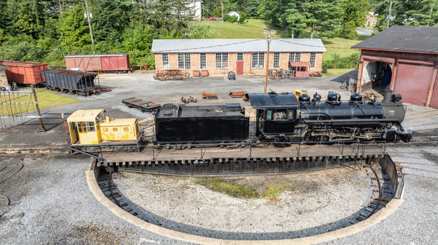 Aerial view of a historic steam locomotive and a yellow diesel locomotive on a turntable at the East Broad Top Railroad yard in Rockhill Pennsylvania United States. Aerial view of a historic steam locomotive and a yellow diesel locomotive on a turntable at the East Broad Top Railroad yard in Rockhill Pennsylvania United States.
