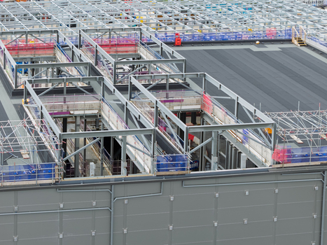 Aerial view of a data center under construction featuring steel framework scaffolding and roofing elements in the United Kingdom.