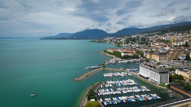 Aerial view of the turquoise lake embracing the city s edge with yachts dotting the marina and mountains looming in the horizon Neuchâtel Neuchâtel Switzerland. Aerial view of the turquoise lake embracing the city s edge with yachts dotting the marina and mountains looming in the horizon Neuchâtel Neuchâtel Switzerland.