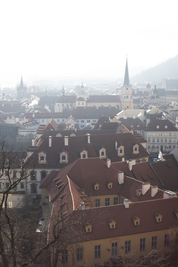 View of historic red tiled rooftops and church spires under a hazy morning sky in the old town Prague Prague Czechia. View of historic red tiled rooftops and church spires under a hazy morning sky in the old town Prague Prague Czechia.